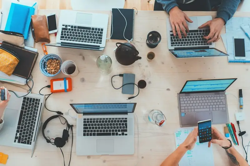 Laptops, notes and phones on a busy project desk